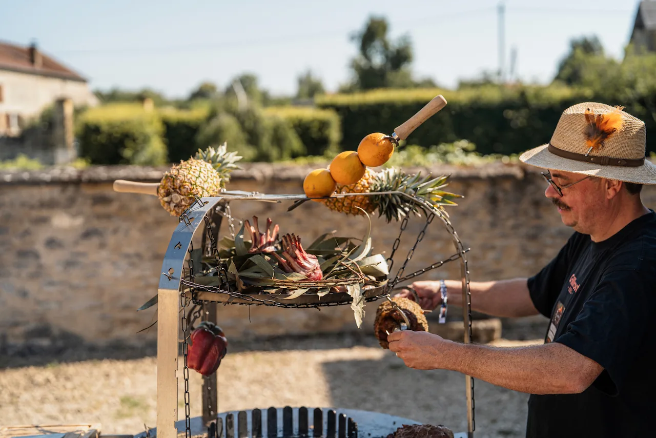 Régis Calcus au foyer ouvert, ananas et agrumes suspendus au-dessus de la braise